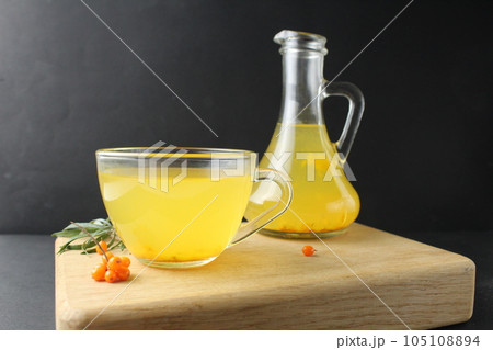 tea juice sea buckthorn yellow color in a cup and carafe on a black background with a place for text and copyspace. healthy vitamin drink tea 105108894