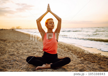 Meditation. Young woman doing yoga near the ocean barefoot. Calmness and balance, healthy lifestyle. 105108943