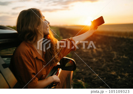 Selfie while traveling. Woman takes selfie in car during road trip. Lifestyle, travel, active life. 105109323