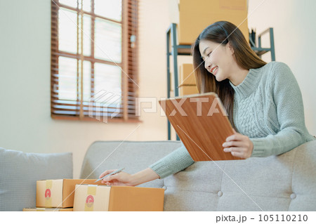 Starting small business entrepreneur of independent young Asian woman online seller is using computer and taking orders to pack products for delivery to customers. SME delivery concept. 105110210