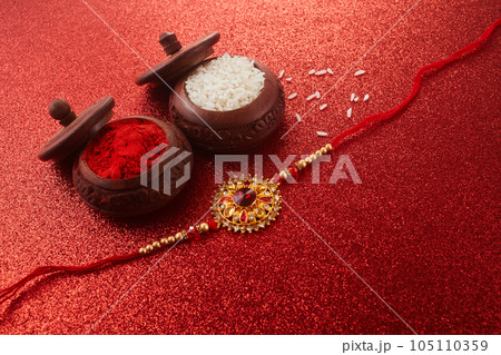 Raksha Bandhan. Rakhi string, Rice Grains and Kumkum on red background. Raksha Bandhan. Rakhi string, Rice Grains and Kumkum on red background. 105110359