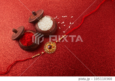 Raksha Bandhan. Rakhi string, Rice Grains and Kumkum on red background. Raksha Bandhan. Rakhi string, Rice Grains and Kumkum on red background. 105110360