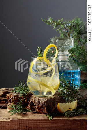 Cocktail gin-tonic with ice, lemon, and rosemary in a frozen glass. 105110438