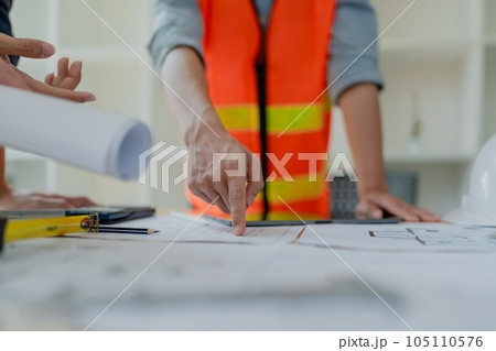 multi ethnic engineer brainstorming and measuring for cost estimating on paperworks and floor plan drawings about design architectural and engineering for houses and buildings. 105110576