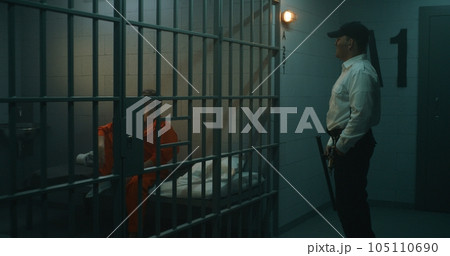 Prison officer walks the corridor, gives phone to female prisoner Prison officer walks the corridor, gives phone to female prisoner 105110690