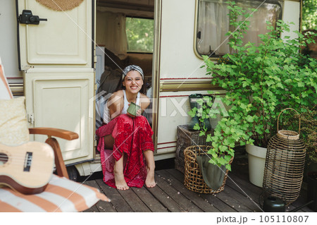 Happy hippie girl are having a good time with cup of tea in camper trailer. Holiday, vacation, trip concept. Happy hippie girl are having a good time with cup of tea in camper trailer. Holiday, vacation, trip concept. 105110807