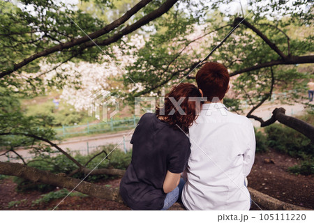 Young couple in love sitting and embracing to enjoy park view. 105111220