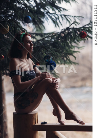 Beautiful girl in bikini sitting against of snow-covered trees in winter 105111511
