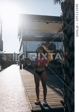 Cute young woman in swimsuit working on laptop on the beach Cute young woman in swimsuit working on laptop on the beach 105111696