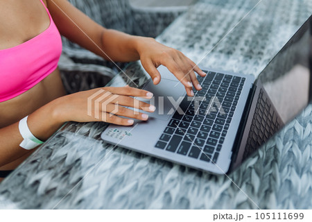 Cute young woman in swimsuit working on laptop sitting on terrace on the beach 105111699