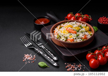 Delicious fresh white boiled rice with vegetables carrots, peppers and asparagus beans on a ceramic plate 105112002