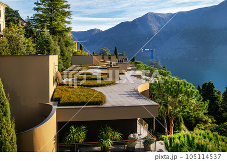 Idyllic garden on roof of 4 storey building and coniferous park on coastline of lake Lugano  in Switerland 105114537