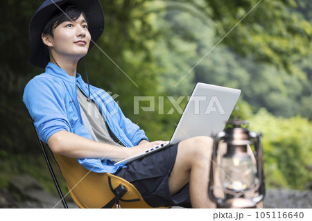 キャンプ場でパソコン作業をする若い男性 キャンプ場でパソコン作業をする若い男性 105116640