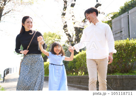 笑い合いながら手を繋いで歩く女の子と両親 笑い合いながら手を繋いで歩く女の子と両親 105118711