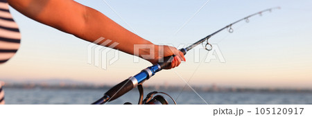 Woman holds spinning rod in her hands and fishing in sea. Woman holds spinning rod in her hands and fishing in sea. 105120917