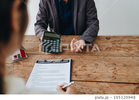 Guarantee, mortgage, contract, contract, signed, real estate agent or bank officer holding a calculator, submits a bid with a customer to buy a home before signing to make a deal. 105120948