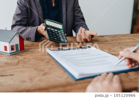Guarantee, mortgage, contract, contract, signed, real estate agent or bank officer holding a calculator, submits a bid with a customer to buy a home before signing to make a deal. Guarantee, mortgage, contract, contract, signed, real estate agent or bank officer holding a calculator, submits a bid with a customer to buy a home before signing to make a deal. 105120966