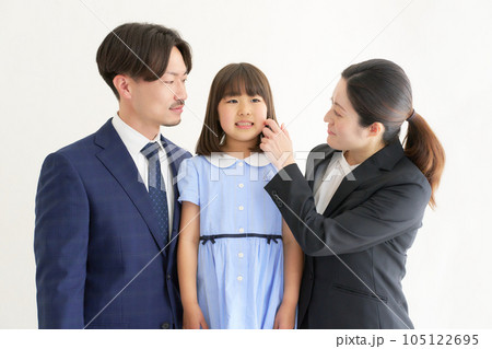 緊張する幼い娘を見守るスーツ姿の両親 105122695