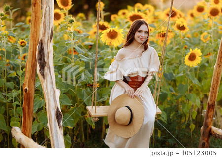 Woman in a dress in a field of sunflowers on a swing 105123005
