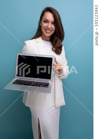 smiling brunette business women in white dress holding laptop for freelancing work 105123841