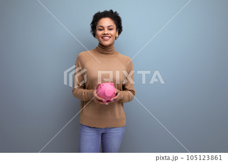 isolated background, cute young brunette hispanic woman freelancer holding piggy bank with coins 105123861