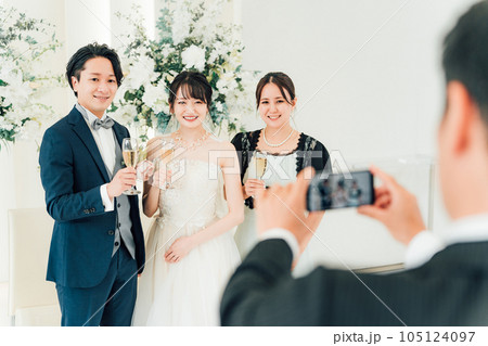 披露宴・パーティーで新郎新婦とスマホで写真を撮る女性 105124097