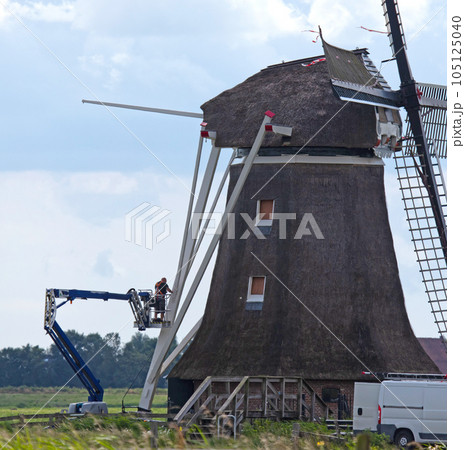 Maintenance engineer doing some work on an old windmill 105125040
