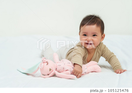 infant baby playing doll on bed infant baby playing doll on bed 105125476