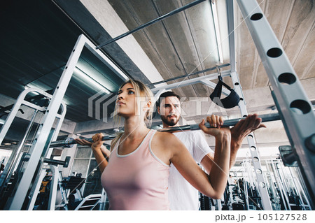 Sport women working out with pull barbell in  fitness gym 105127528