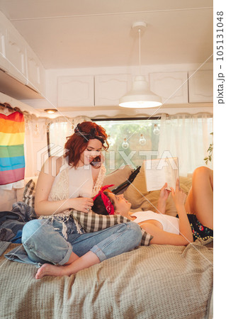 Portrait of a cute lesbian couple. Two girls spend time tenderly together in a camper trailer. Love and attitude. LGBT concept Portrait of a cute lesbian couple. Two girls spend time tenderly together in a camper trailer. Love and attitude. LGBT concept 105131048