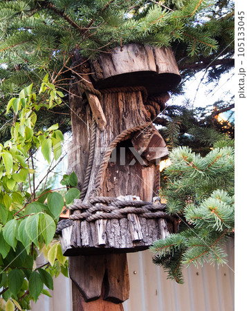 Details of the garden interior. Stylization of the head of an ancient idol, carved from a piece of a tree trunk, close-up. Details of the garden interior. Stylization of the head of an ancient idol, carved from a piece of a tree trunk, close-up. 105133045