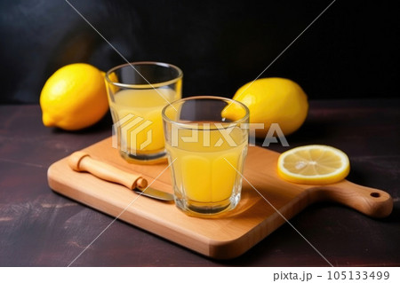 Two glass cups of fresh lemon juice and wooden reamer. Generative AI 105133499