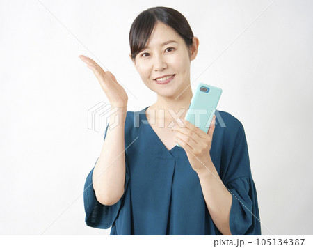 スマートフォンを持って左側を手のひらで指す女性　白背景 105134387