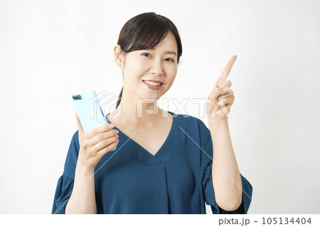 スマートフォンを持って右側を指差す女性 白背景 スマートフォンを持って右側を指差す女性 白背景 105134404