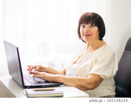 Smiling business woman working at her computer at home. Business, education and technology concept. 105136224