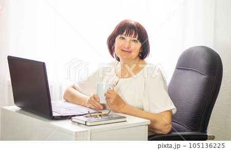 Smiling business woman working at laptop at home and drinking coffee. Business and education concept 105136225