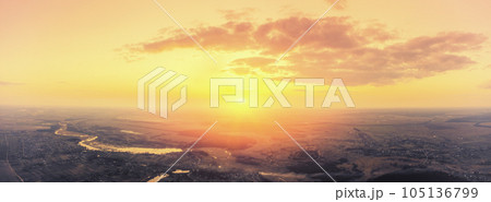 Beautiful sunset in the countryside in spring with the blazing sky. Rural landscape in the evening. Aerial view of brook, village, and arable fields. Panoramic view Beautiful sunset in the countryside in spring with the blazing sky. Rural landscape in the evening. Aerial view of brook, village, and arable fields. Panoramic view 105136799