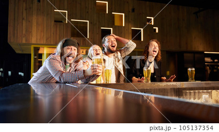 Young emotional people, friends, sport fans visiting bar, drinking beer, watching sport match translation 105137354