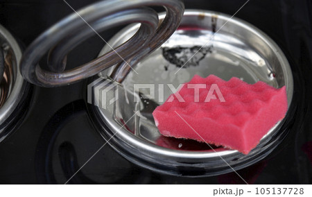 Cleaning the electric stove with a pink brush. Cleaning the kitchen stove. Cleaning the electric stove with a pink brush. Cleaning the kitchen stove. 105137728