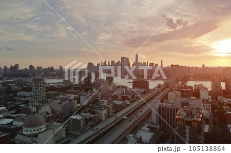 During sunset is panoramic view visible Manhattan across East River crossed by Williamsburg Bridge in New York city During sunset is panoramic view visible Manhattan across East River crossed by Williamsburg Bridge in New York city 105138864