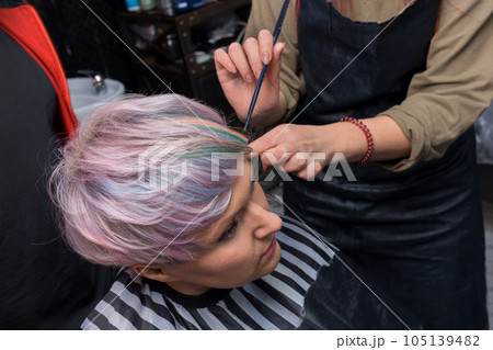 The hands of a girl of an experienced barbershop professional worker in the process of creating a stylish fashionable bob hairstyle creative color coloring The hands of a girl of an experienced barbershop professional worker in the process of creating a stylish fashionable bob hairstyle creative color coloring 105139482