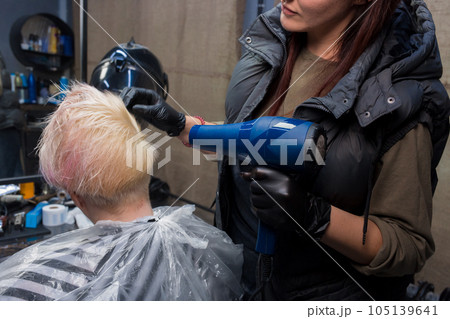 Hand in the glove of an experienced salon worker girl blow drying hair to a woman client hairdressing services Hand in the glove of an experienced salon worker girl blow drying hair to a woman client hairdressing services 105139641