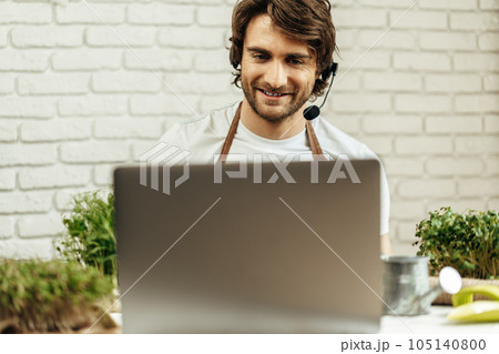 Handsome bearded man sells plant sprouts and seedlings online using laptop 105140800