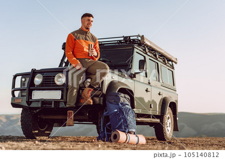 Young man traveler drinking from his thermocup while halt on a hike 105140812