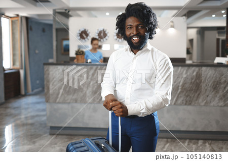 Black businessman with packed luggage standing in hotel lobby Black businessman with packed luggage standing in hotel lobby 105140813