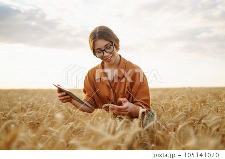 Farmer- woman on wheat field with tablet in his hands. Smart farm. Agriculture, gardening concept. 105141020