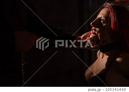 BDSM. A man holds a kneeling woman by the chin.  105141430