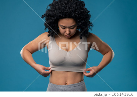 Waist up picture of woman in a bra standing on a blue background Waist up picture of woman in a bra standing on a blue background 105141916