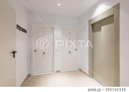 Foyer with the entrance to the apartments premises and an elevator in a new building in light colors. The concept of prestigious expensive housing in a European city. Translation: first 105142330