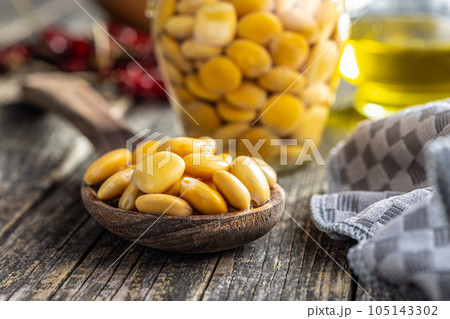 Lupini beans in brine. Pickled lupin in spoon on wooden table. Lupini beans in brine. Pickled lupin in spoon on wooden table. 105143302